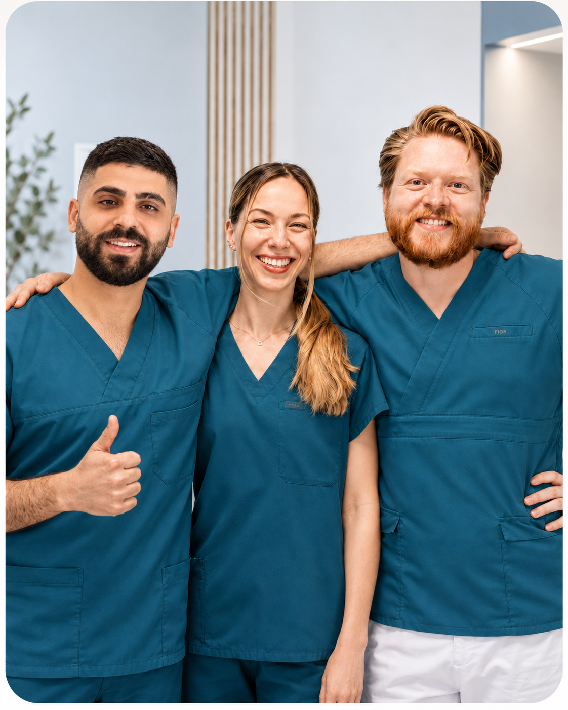 Tre smilende medlemmer av tannhelseteamet hos Bergen Tannklinikk står sammen i klinikken, kledd i blågrønne uniformer.